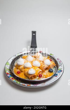 Frittelle con meringa e frutti di bosco in padella su sfondo bianco. Foto Stock