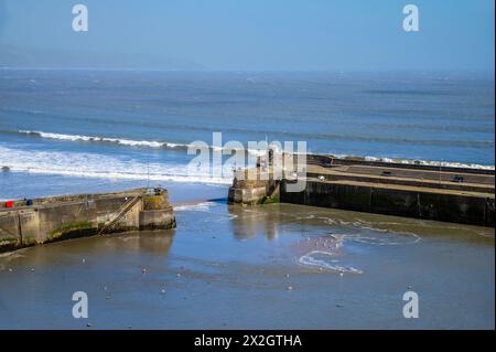 Una vista che guarda in basso verso l'entrata del porto con la bassa marea a Saundersfoot, Galles, in una luminosa giornata primaverile Foto Stock