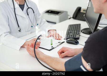 Un esperto medico si concentra sulla scrittura delle informazioni vitali in un ambiente clinico. Foto Stock