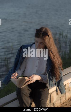 Ritratto di una bella ragazza con un libro. Sta succedendo da qualche parte nel parco. Primo piano. Foto Stock