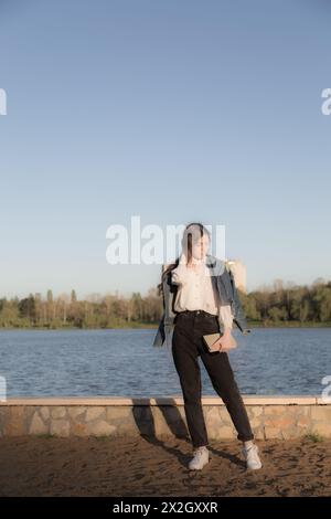 Ritratto di una bella ragazza con un libro. Sta succedendo da qualche parte nel parco. Primo piano. Foto Stock