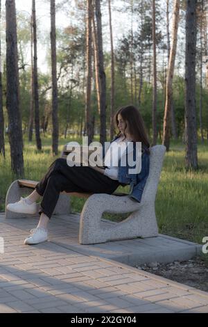 Ritratto di una bella ragazza con un libro. Sta succedendo da qualche parte nel parco. Primo piano. Foto Stock