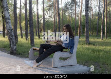 Ritratto di una bella ragazza con un libro. Sta succedendo da qualche parte nel parco. Primo piano. Foto Stock