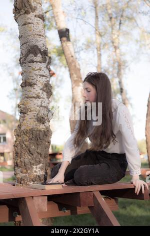 Ritratto di una bella ragazza con un libro. Sta succedendo da qualche parte nel parco. Primo piano. Foto Stock