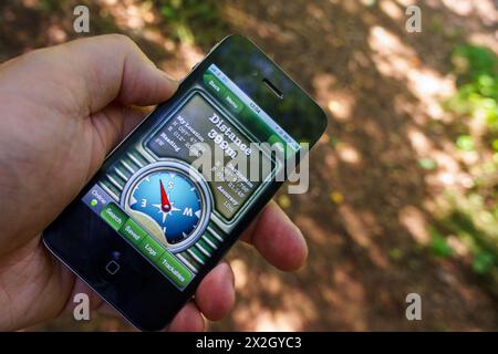 Vista ravvicinata della mano di un uomo adulto tramite l'app di navigazione GPS su iPhone che visualizza la direzione della bussola Foto Stock