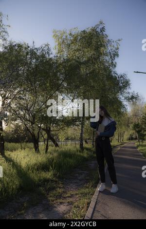 Ritratto di una bella ragazza con un libro. Sta succedendo da qualche parte nel parco. Primo piano. Foto Stock