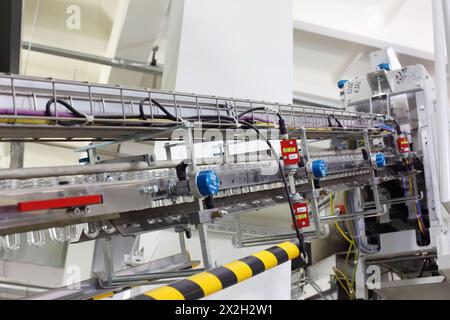Trasportatore con preforme in plastica per la produzione di bottiglie in PET nel reparto della grande fabbrica Foto Stock