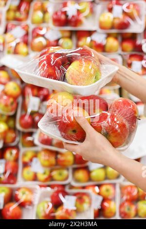 donna mani tenere le mele in negozio; donna sceglie cibo gustoso e sano; profondità di campo bassa Foto Stock