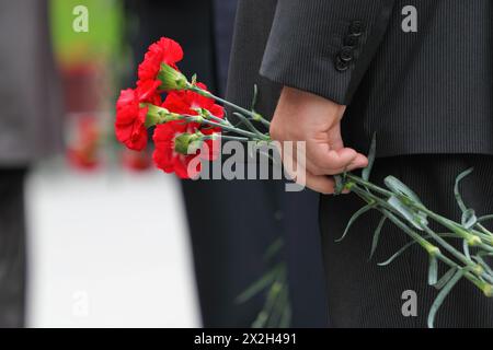 Bouquet di garofani rossi in mano all'uomo durante le celebrazioni del giorno della Vittoria; concentrati sui fiori Foto Stock