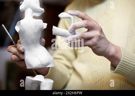 Le mani dello scultore tengono parti di statuetta in gesso. Foto Stock