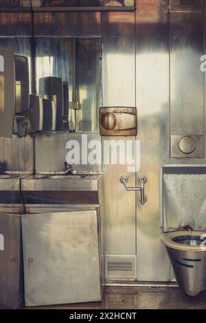 Vecchio bagno pubblico sporco con interni metallici, immagine verticale Foto Stock