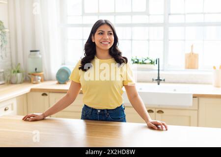 Felice donna araba appoggiata al bancone della cucina Foto Stock