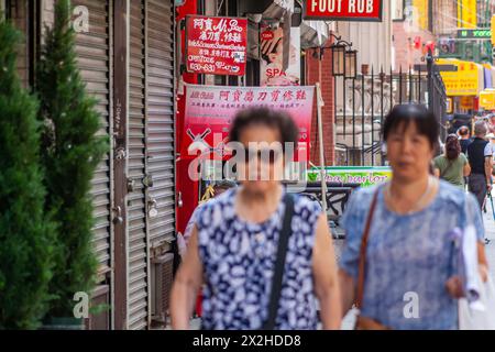 Vivace strada cittadina con pedoni fuori fuoco e vetrine a Chinatown, New York City. Foto Stock