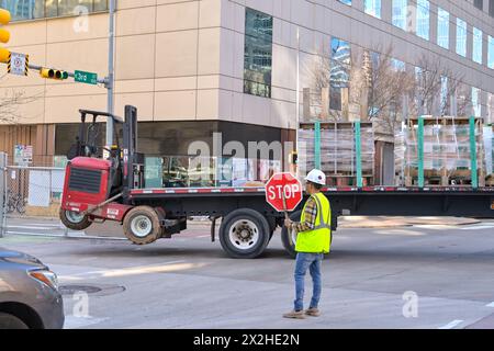 Austin, Texas, Stati Uniti - 8 febbraio 2023: Operaio edile con un segnale di stop per fermare il traffico mentre un autocarro articolato torna in cantiere Foto Stock