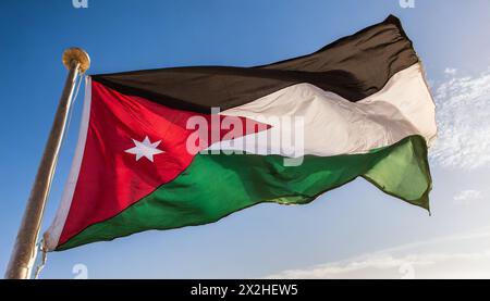 Die Fahne von Jordanien flattert im Wind, isoliert gegen blauer Himmel Foto Stock