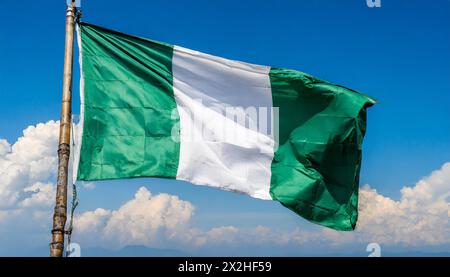 Die Fahne von Nigeria flattert im Wind, isoliert gegen blauer Himmel Foto Stock