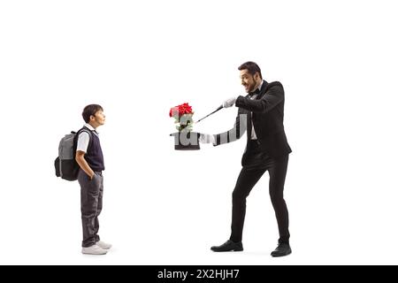 Ragazzo che guarda un mago che esegue un trucco con cappello e rose rosse isolate su sfondo bianco Foto Stock