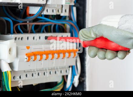 Primo piano del tecnico elettricista lavora con cavi elettrici della scatola fusibili. Apparecchiature elettriche e automatiche. Foto Stock