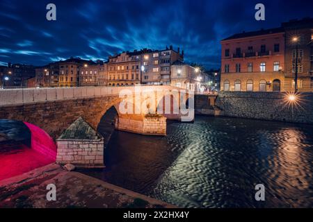 Un punto di riferimento storico che si estende lungo il fiume Miljacka, immerso nel bagliore crepuscolo della sera, offre uno sguardo sul passato medievale della città. Foto Stock