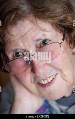 Ritratto di una donna anziana sorridente con gli occhiali nel suo salotto, primo piano, Colonia, Renania settentrionale-Vestfalia, Germania Foto Stock