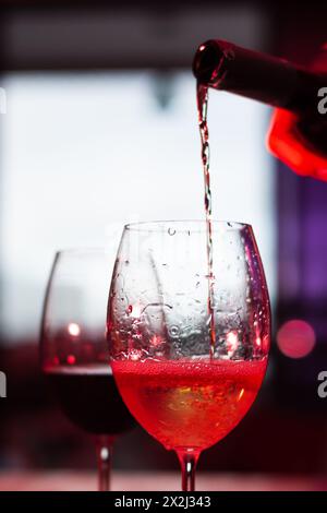 Silhouette di due bicchieri da bicchiere con vino su un tavolo di legno. Bottiglia che serve un bicchiere. E' ora di rilassarsi. Foto Stock