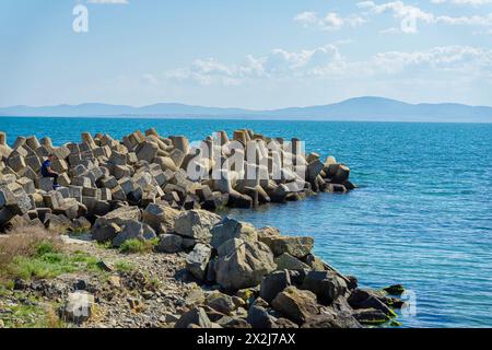 Paesaggio marino con pietre frantumatrici in cemento ricoperte da frantumatori a onde per proteggerli Foto Stock