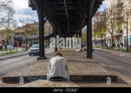 Berlino, Germania - 01 aprile 2024: Ponte e ferrovia a Kreuzberg. Un uomo si siede sotto un ponte a leggere un libro. Vista dal retro. Foto Stock