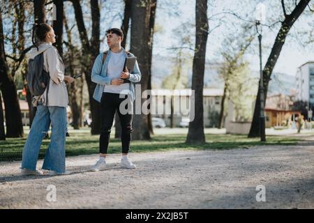 Studenti adolescenti che chiacchierano in un parco soleggiato, amici con zaini che si godevano una pausa Foto Stock