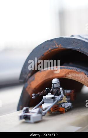Le minifigure LEGO Mandalorian e Baby Yoda (Grogu) attraversano un tunnel scuro con sfondo sfocato Foto Stock