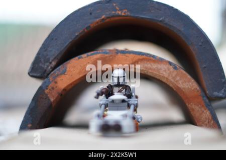 Le minifigure LEGO Mandalorian e Baby Yoda (Grogu) attraversano un tunnel con sfondo sfocato Foto Stock