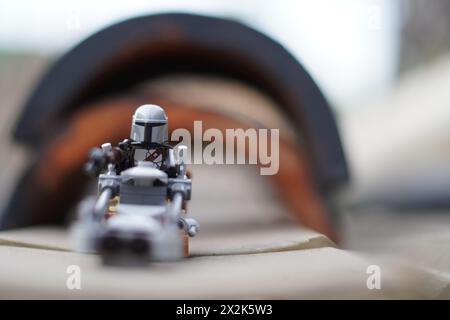 Le minifigure LEGO Mandalorian e Baby Yoda (Grogu) attraversano un tunnel con sfondo sfocato Foto Stock