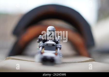 Le minifigure LEGO Mandalorian e Baby Yoda (Grogu) attraversano un tunnel con sfondo sfocato Foto Stock