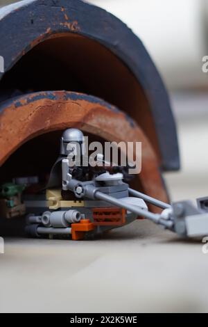 Le minifigure LEGO Mandalorian e Baby Yoda (Grogu) attraversano un tunnel scuro con sfondo sfocato Foto Stock