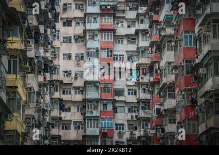 Una vista ravvicinata di un edificio residenziale densamente affollato a Hong Kong, con una miriade di finestre, condizionatori d'aria e lavanderia sospesa. Foto Stock