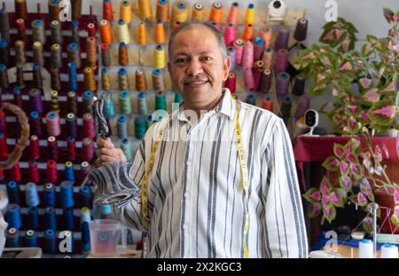 Uomo latino di 50 anni nel suo laboratorio di cucito e design di moda Foto Stock