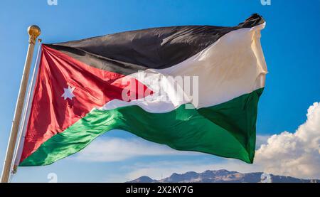 Die Fahne von Jordanien flattert im Wind, isoliert gegen blauer Himmel Foto Stock