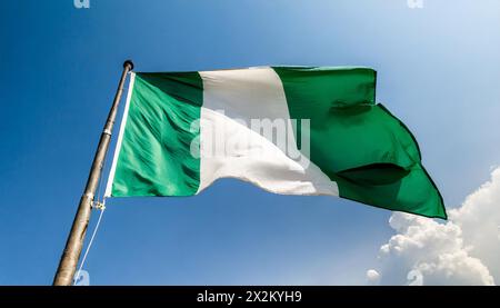 Die Fahne von Nigeria flattert im Wind, isoliert gegen blauer Himmel Foto Stock