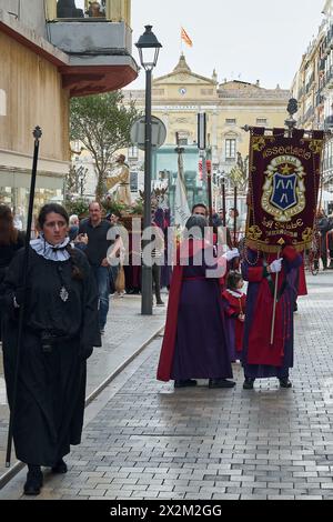 Tarragona, Spagna - 23 aprile 2024: Evento culturale della settimana Santa con figure religiose e devoti in abiti cerimoniali che si muovono attraverso un'area urbana. Foto Stock