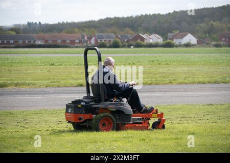 Uomo che utilizza un rasaerba Kubota presso Wellesbourne Airfield, Warwickshire, Regno Unito Foto Stock