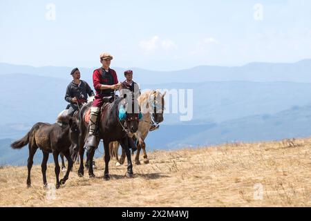 A Illinden (Festa della Repubblica), i ciclisti vestiti tradizionalmente viaggiano da Skopje, la capitale, a Meckin. Kamen, Macedonia del Nord Foto Stock