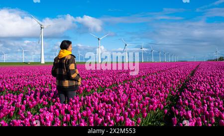 Una donna si erge graziosamente in un mare di tulipani viola, circondato dai vibranti colori della primavera nei Paesi Bassi. Foto Stock