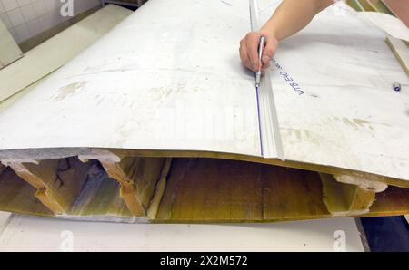 12 aprile 2024, Sassonia, Lipsia: Nel centro tecnico del campus dell’Università di scienze applicate (HTWK), l'assistente alla ricerca Dimitrij Seibert del team guidato dal professore HTWK di costruzione leggera con materiali compositi Robert Böhm prepara una parte di una pala del rotore della turbina eolica di 25 anni smontata per una prova delle sue proprietà meccaniche. Le indagini fanno parte di EuReCOMP, un progetto di ricerca collaborativa finanziato dall'UE che mira a sviluppare metodi sostenibili per il riciclaggio e il riutilizzo di materiali compositi provenienti da componenti dell'energia eolica, tra l'altro. Scienziati Foto Stock