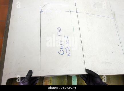 12 aprile 2024, Sassonia, Lipsia: Nel centro tecnico del campus dell’Università di scienze applicate (HTWK), l'assistente alla ricerca Dimitrij Seibert del team guidato dal professore HTWK di costruzione leggera con materiali compositi Robert Böhm prepara una parte di una pala del rotore della turbina eolica di 25 anni smontata per una prova delle sue proprietà meccaniche. Le indagini fanno parte di EuReCOMP, un progetto di ricerca collaborativa finanziato dall'UE che mira a sviluppare metodi sostenibili per il riciclaggio e il riutilizzo di materiali compositi provenienti da componenti dell'energia eolica, tra l'altro. Scienziati Foto Stock