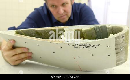 12 aprile 2024, Sassonia, Lipsia: Nel centro tecnico del campus dell'Università di Scienze applicate (HTWK), il professore di costruzione leggera con materiali compositi di HTWK Robert Böhm esamina una parte di una pala del rotore di turbina eolica smontata di 25 anni, che è stata preparata per una prova delle proprietà meccaniche. Le indagini fanno parte di EuReCOMP, un progetto di ricerca collaborativa finanziato dall'UE che mira a sviluppare metodi sostenibili per il riciclaggio e il riutilizzo di materiali compositi provenienti da componenti dell'energia eolica, tra l'altro. Scienziati di college, università e instit Foto Stock