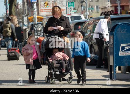 Una scena di strada in un quartiere ebraico a Brooklyn dove una madre e i suoi figli si fermano mentre legge quello che sembra essere un foglio di istruzioni. Foto Stock