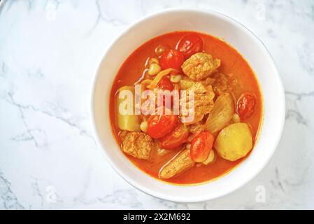 Curry Massaman di maiale, curry tailandese con il sapore dolce e un po' piccante. Immagine del curry massamano su un tavolo di marmo bianco con natura Foto Stock