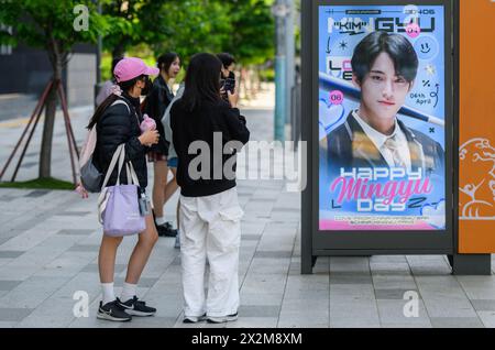 I fan del K-pop scattano foto di un cartellone pubblicitario del cantante di Hybe Mingyu di fronte all'edificio Hybe a Seoul. La più grande società K-pop della Corea del Sud Hybe ha lanciato un audit del management di ADOR, l'etichetta sussidiaria dietro NewJeans, un gruppo di ragazze K-pop, con il sospetto che l'etichetta cercasse di staccarsi da Hybe, secondo fonti del settore. Le fonti hanno affermato che l'audit si rivolge al CEO DI ADOR, min Hee-jin, e a un altro dirigente della società la cui identità non è stata divulgata, per il sospetto tentativo di prendere il controllo della società. Foto Stock