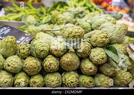 Mazzo di carciofi verdi freschi in vendita presso un mercato agricolo locale con un cartello di prezzo Foto Stock