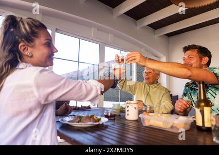 Una famiglia multigenerazionale si diverte a fare un barbecue con un brindisi, con la nonna al centro, una donna a sinistra e un uomo a destra Foto Stock