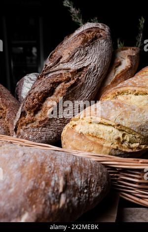 Una selezione di pane fresco e croccante a lievitazione naturale, con orgoglio fatto a mano, disposti in un cestino rustico di vimini. Foto Stock